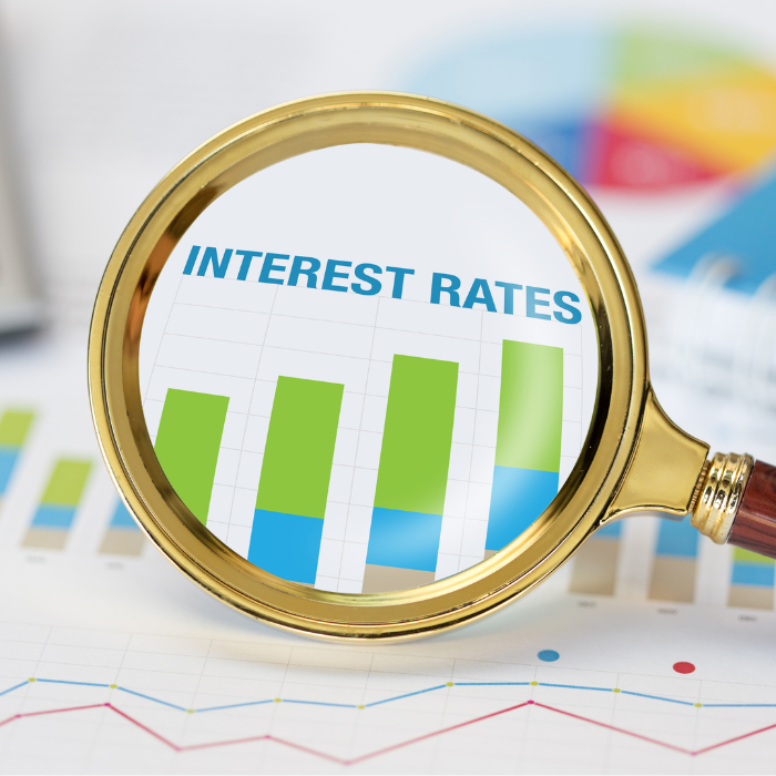 Magnifying glass over a chart labeled Interest Rates with rising green bar graphs in view